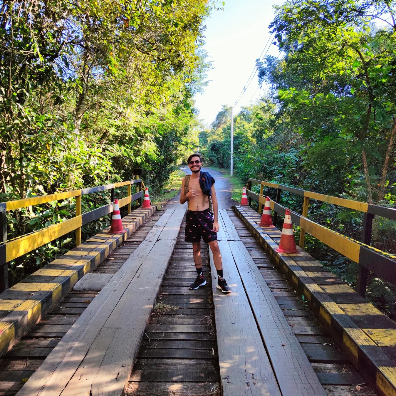 Matheus Ché sobre uma ponte de madeira em meio à mata